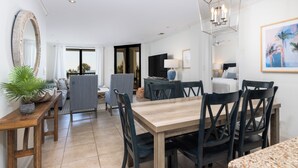 Un'area pranzo moderna con tavolo e sedie in legno, un grande specchio e un lampadario.