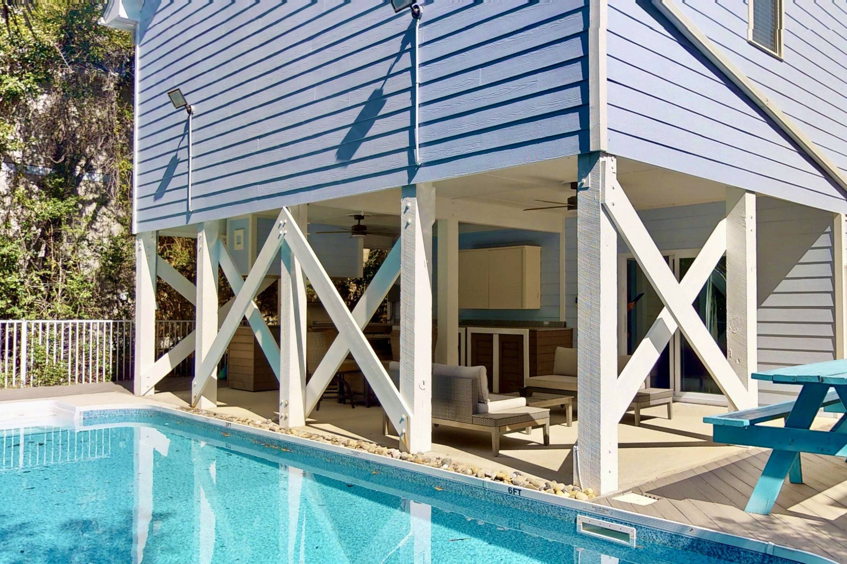 A poolside area with a covered patio, outdoor furniture, and a clear blue pool.