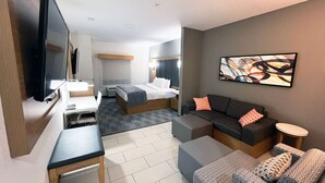 Moderni hotellihuone, jossa on sänky, sohva, työpöytä ja televisio.
