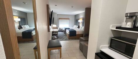 A hotel room with two beds, a small table, a microwave, and a coffee machine.