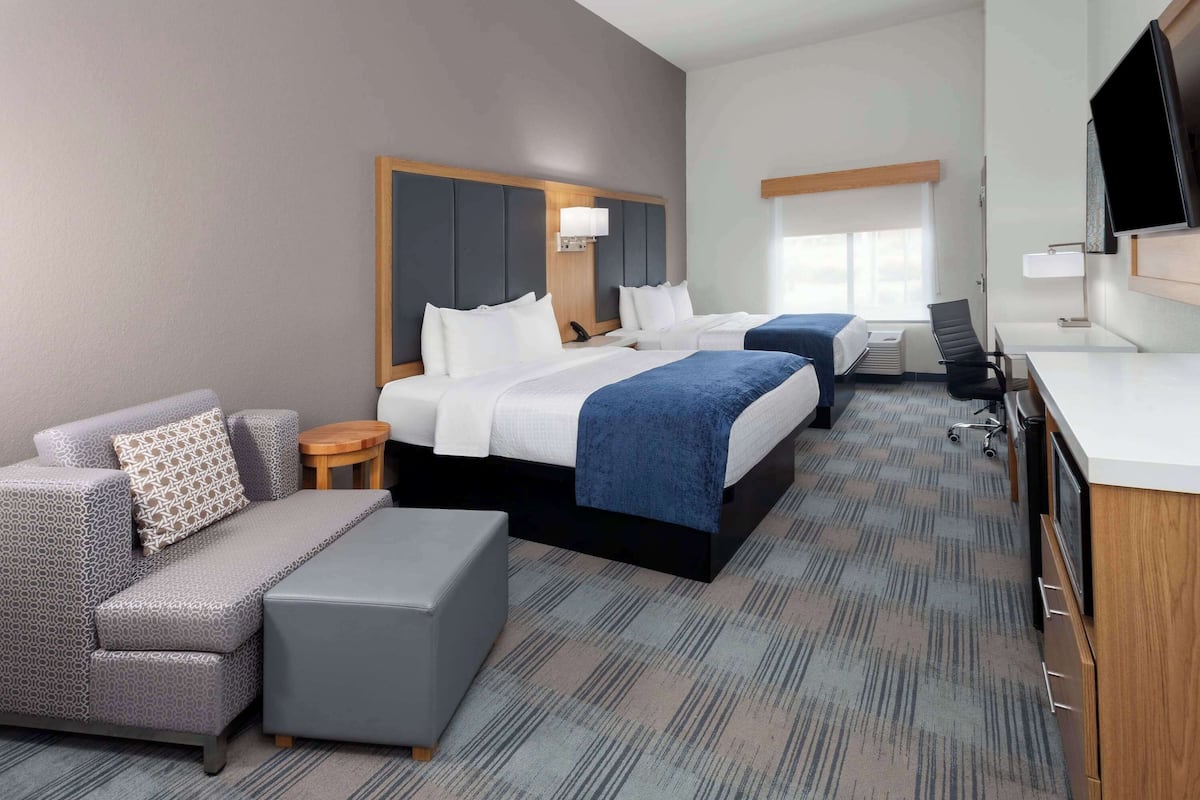 Una habitación de hotel con una cama grande, un sofá, un escritorio y un televisor.