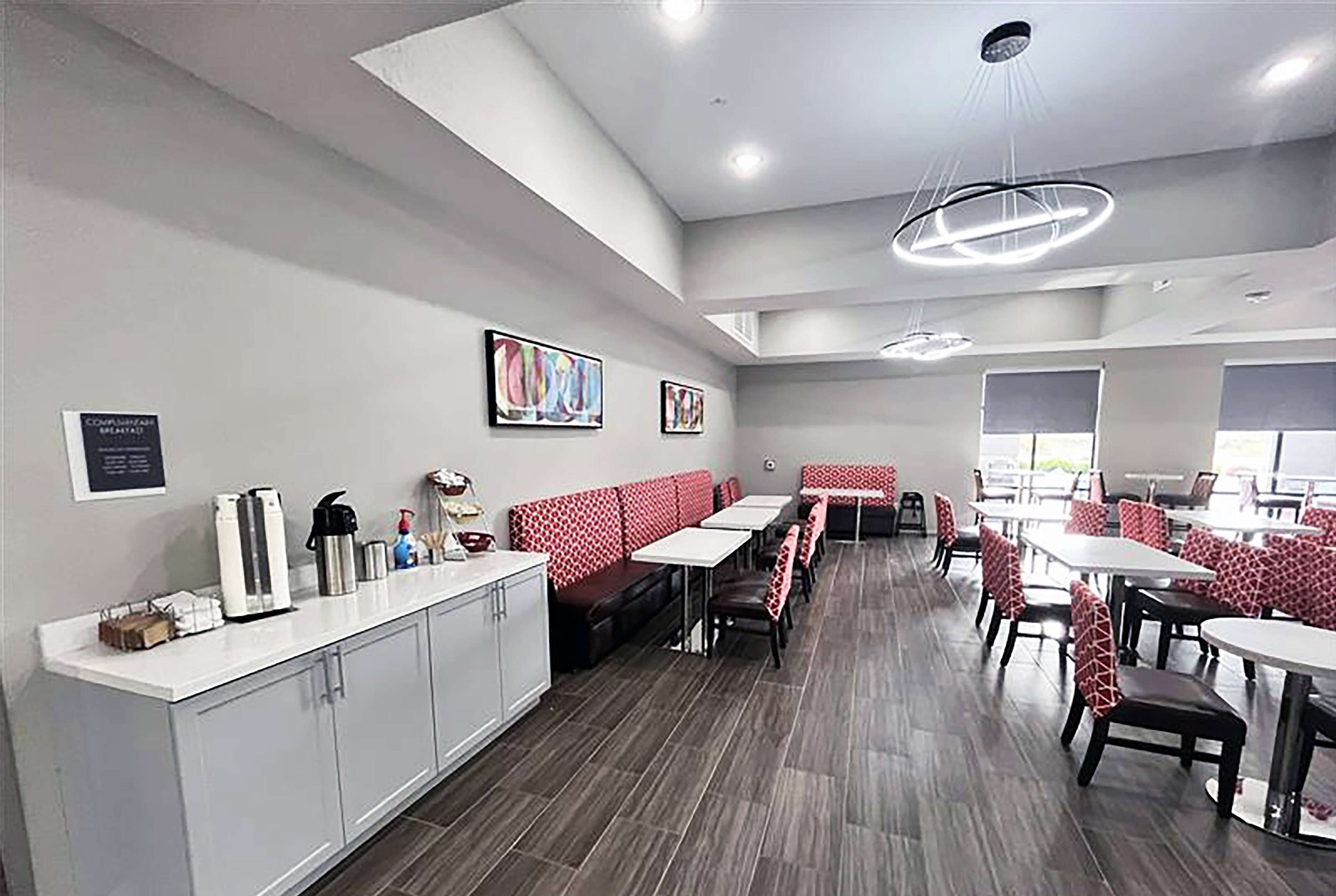 Un restaurant moderne avec de longues tables communes et des banquettes, un comptoir blanc équipé d’appareils de cuisine et des œuvres d’art accrochées aux murs.