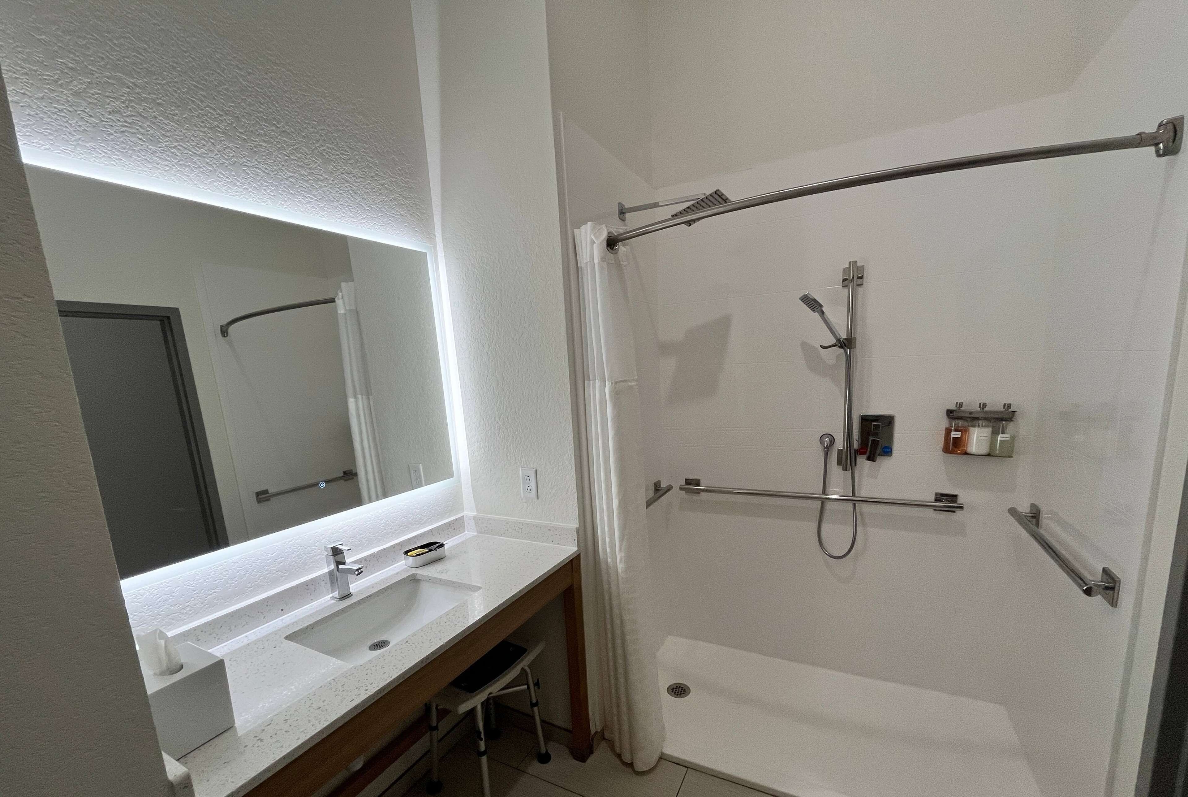 A bathroom with a white sink, mirror, and shower area.