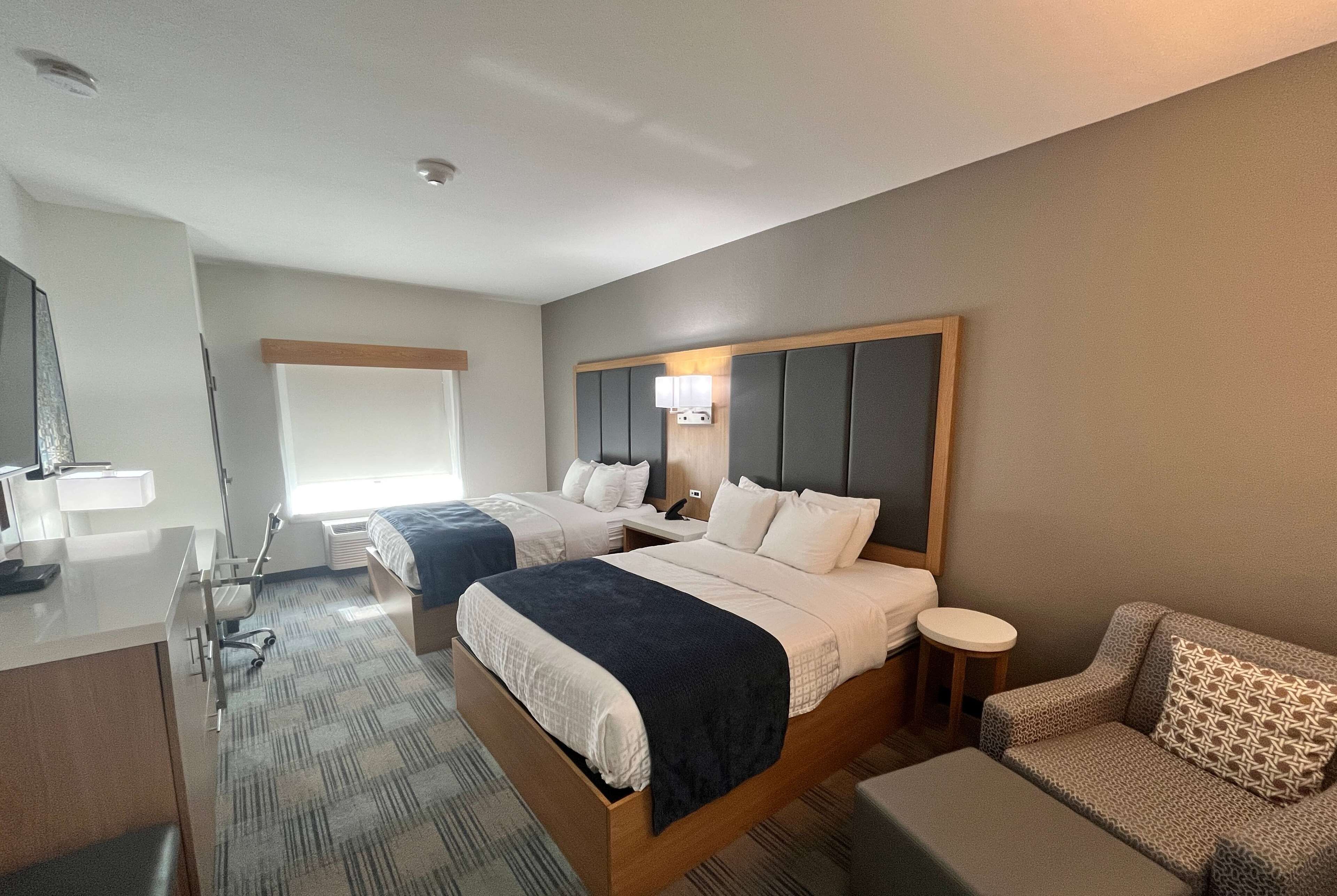 Une chambre d’hôtel avec deux lits, un bureau, une chaise et un canapé.