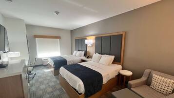 Une chambre d’hôtel avec deux lits, un bureau, une chaise et un canapé.
