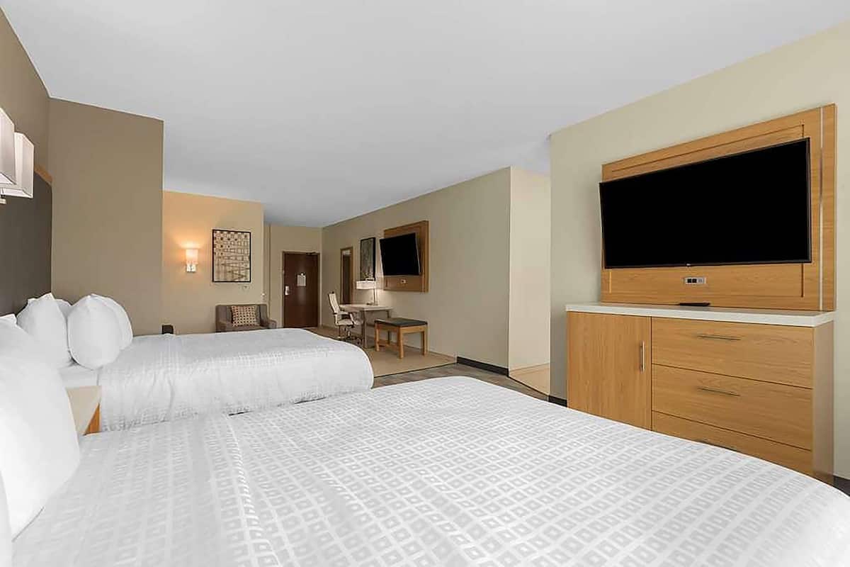 Una habitación de hotel con dos camas, televisión, escritorio y una silla.