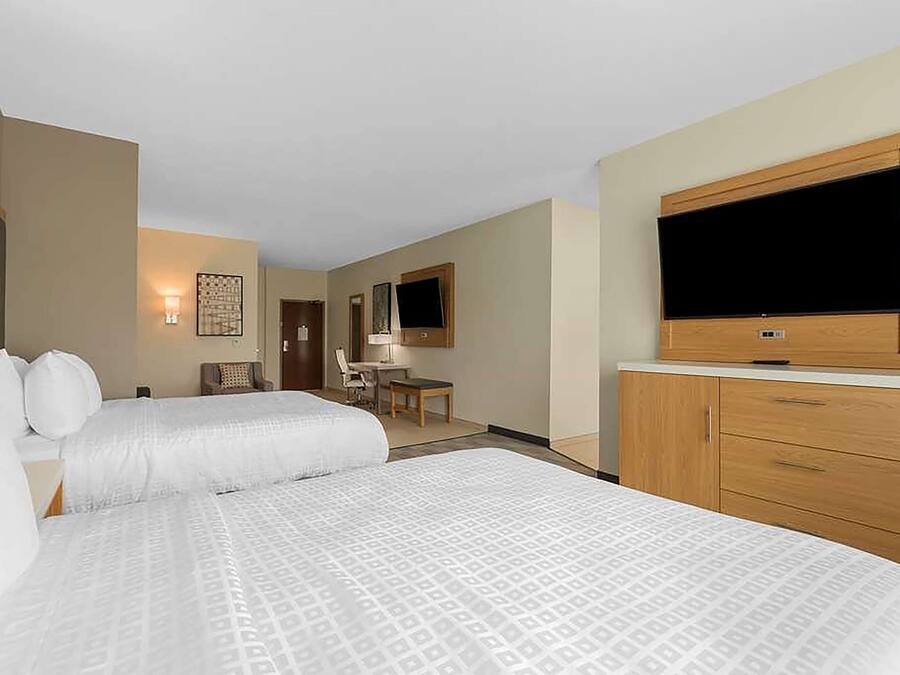 A hotel room with two beds, a TV, a desk, and a chair.