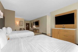 Una habitación de hotel con dos camas, televisión, escritorio y una silla.