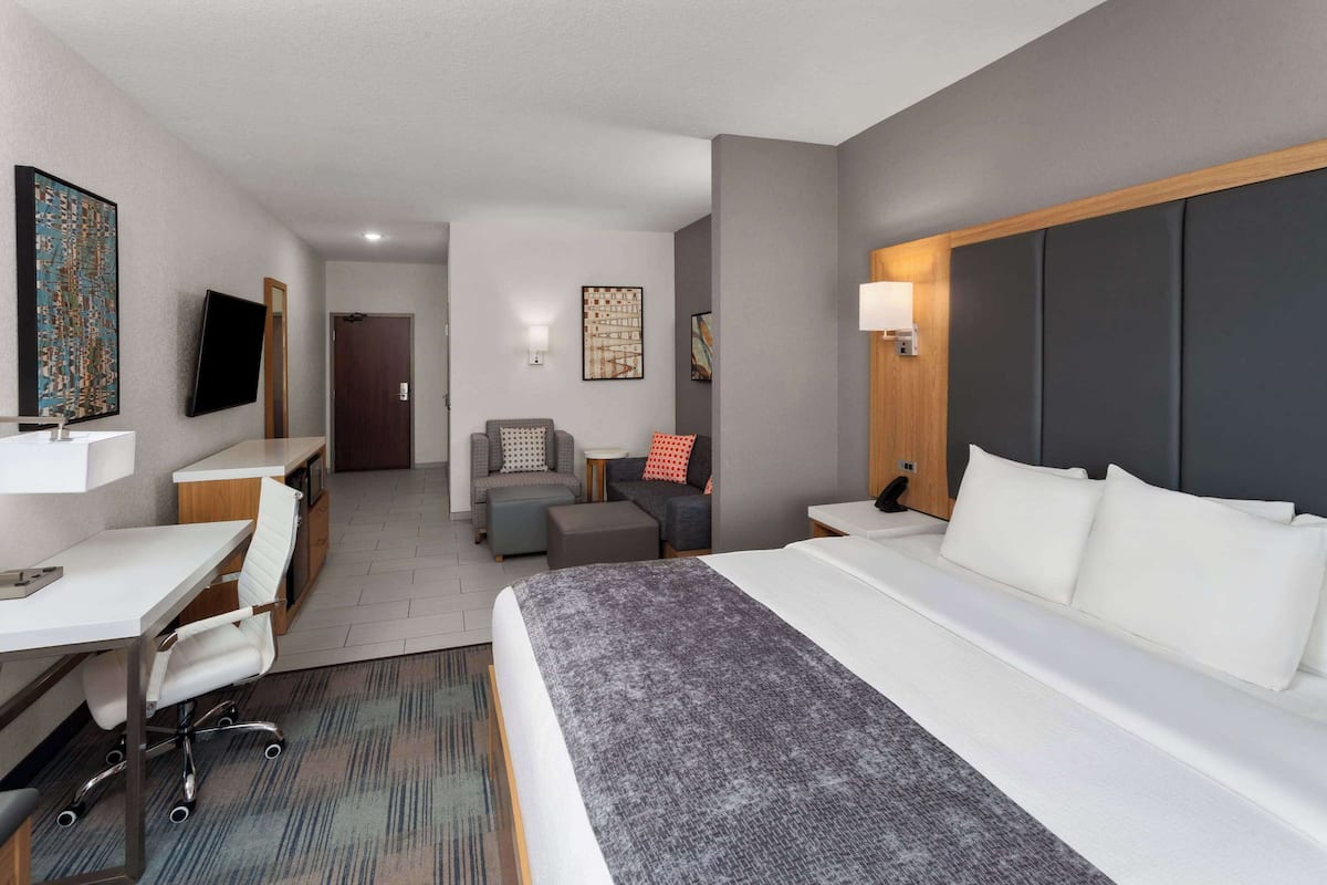 Habitación de hotel con cama, escritorio, silla, sofá y televisor.