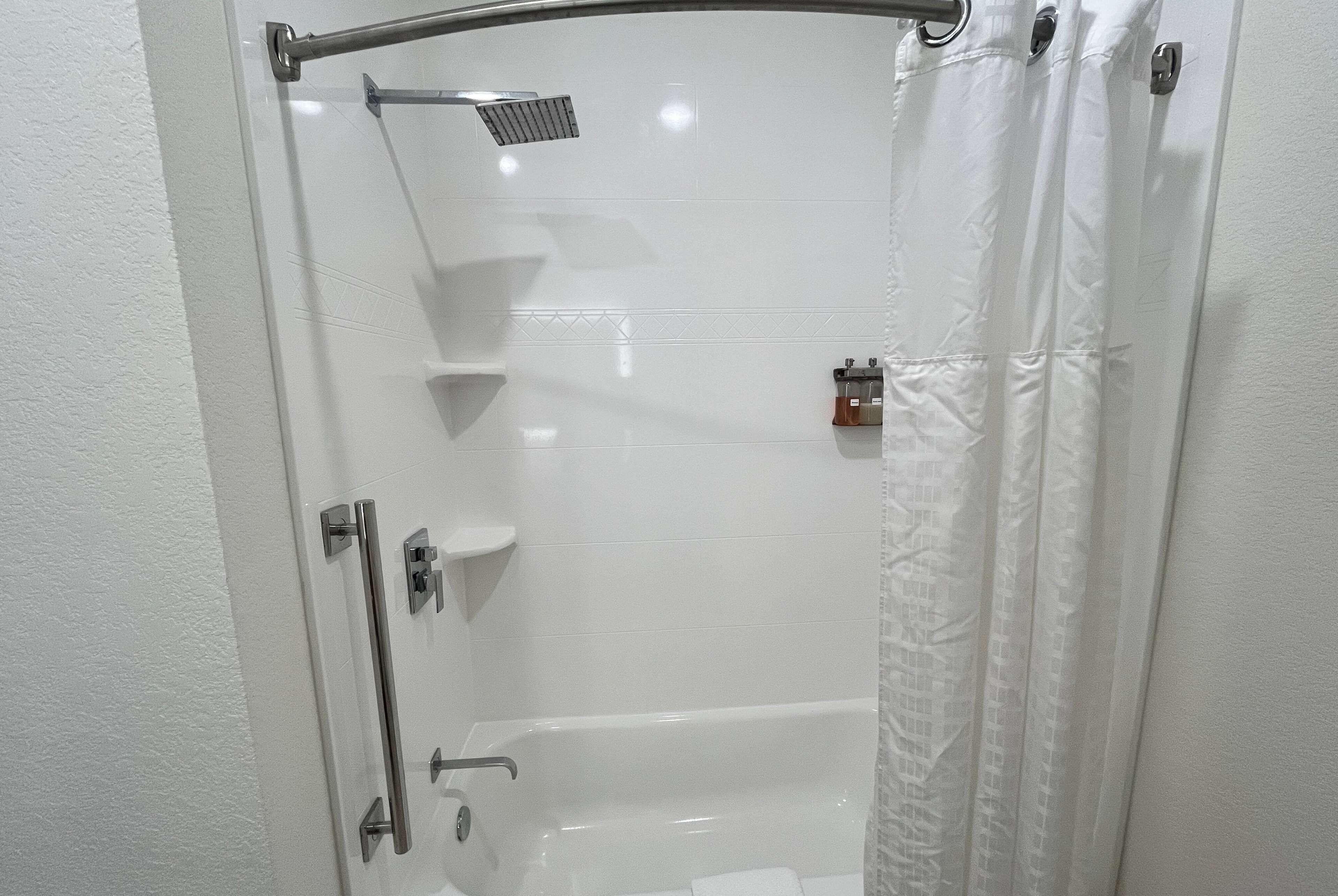 A modern shower area with a glass door, a handheld showerhead, and a towel rack.