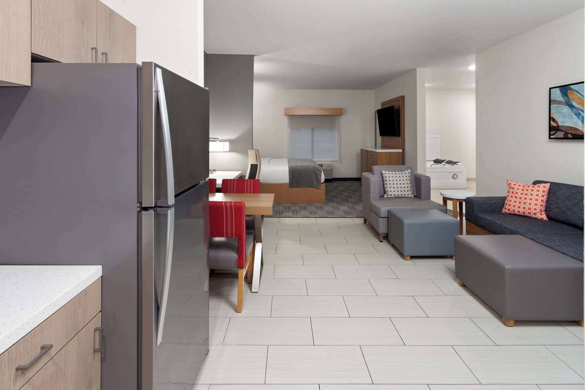Una habitación de hotel moderna con kitchenette, comedor, sofá y televisión.
