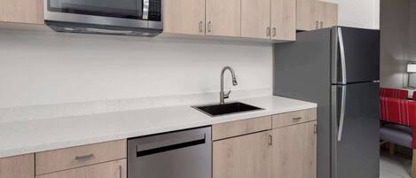 A modern kitchen with a built-in microwave, stainless steel refrigerator, and dishwasher.
