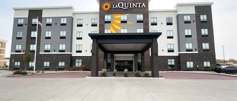 Un hotel moderno a più piani, con un logo ben visibile e un ingresso coperto.