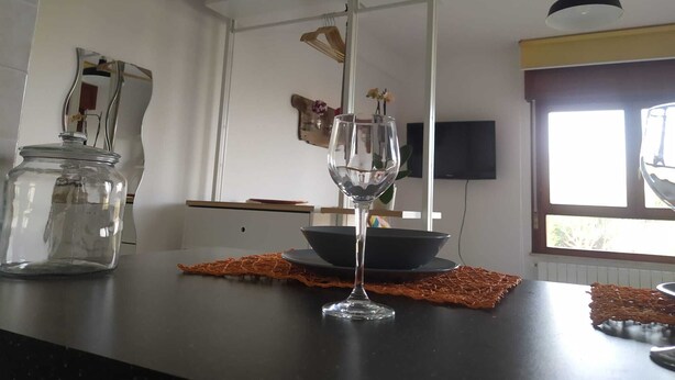 A kitchen with a glass jar on the counter, a wine glass, and a bowl on a woven placemat. - Monolocale La Fornacetta (Pisa)