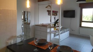 A modern kitchen with two pendant lights, a dining table set with plates and glasses, and a television mounted on the wall. - Monolocale La Fornacetta (Pisa)