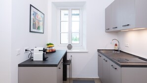 Una cocina moderna con encimera negra, armarios blancos, una ventana y un lavamanos.