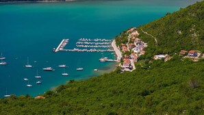 A coastal marina with boats, a pier, and a hillside settlement with houses.