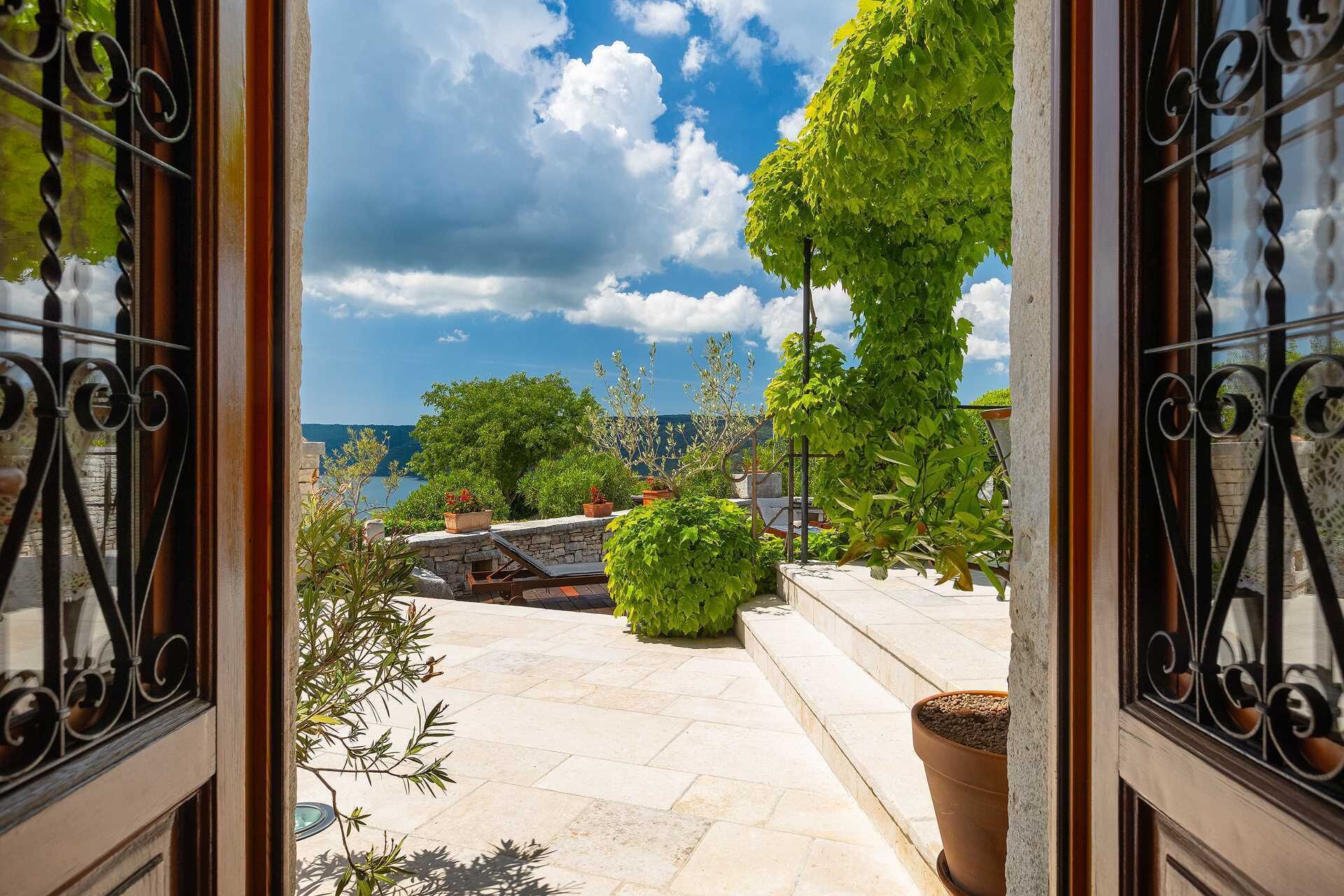 A stone patio with potted plants and a view of the sea.