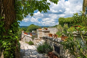 Un patio de piedra con plantas en macetas y vista al paisaje.