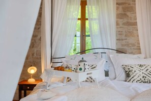 Un dormitorio acogedor con cama, mesita de noche, lámpara y ventana con cortinas.