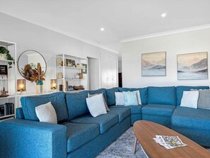 A modern living room with a sectional sofa, a coffee table, and a bookshelf.