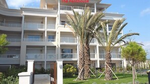 A multi-story hotel named "The Penthouse" with balconies and palm trees in the foreground. - Royal Palm Penthouse (Cannes)