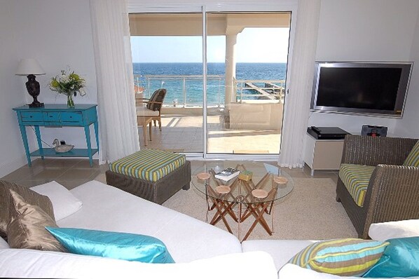 A hotel room with a large bed, a sofa, a TV, and a balcony with a view of the sea. - Royal Palm Penthouse (Cannes)