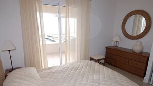 A bedroom with a bed, a dresser, a lamp, and a mirror. - Royal Palm Penthouse (Cannes)