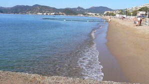 A beach with clear water, pebbly shore, and distant mountains. - Royal Palm Penthouse (Cannes)