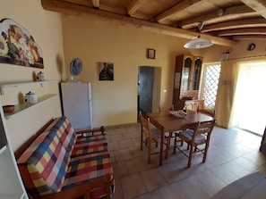 Une cuisine chaleureuse avec une table en bois, des chaises, un réfrigérateur et un canapé aux couleurs vives.