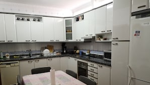 Una cocina compacta con armarios blancos, un microondas y un refrigerador.