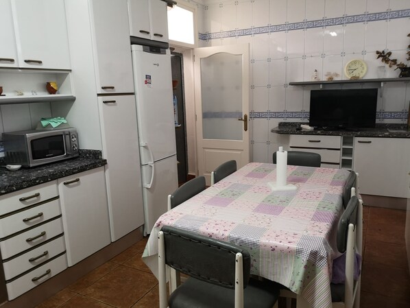 A compact kitchen with a microwave, refrigerator, and a dining table with chairs.
