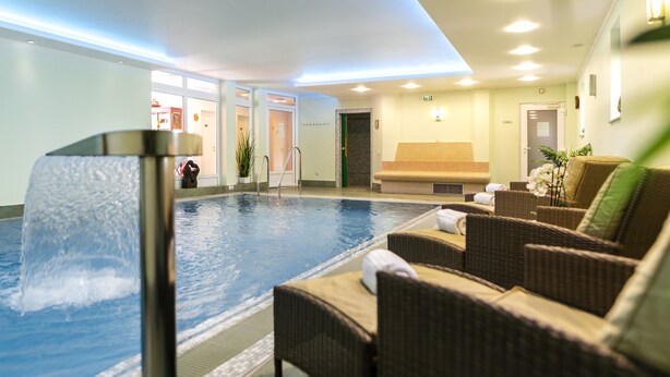 An indoor swimming pool with lounge chairs and a reception area. - Villa Ulmenhof (Bredstedt)