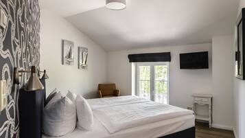 A bedroom with a bed, a chair, a TV, and a window with a view.