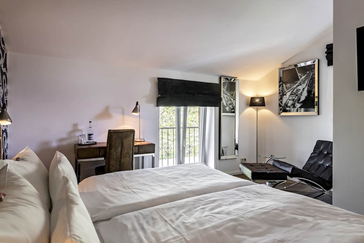 A hotel room with a large bed, a desk, a chair, and a window with a view.