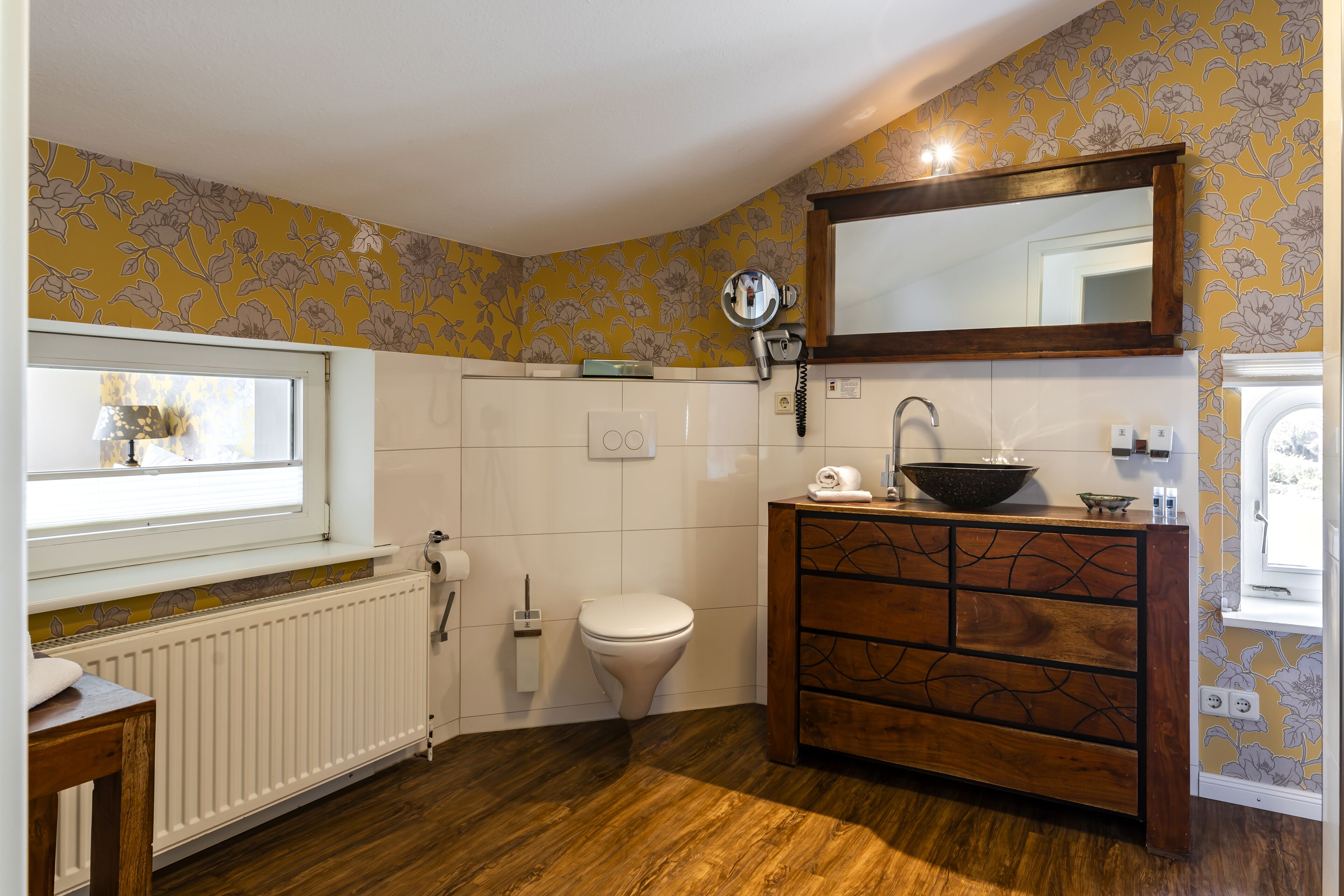 Et badeværelse med en trækommode, toilet og et vindue.