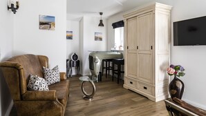 A living room with a brown leather sofa, a glass coffee table, and a vintage radio. There is a large wooden cabinet and a flat-screen TV mounted on the wall. - Villa Ulmenhof (Bredstedt)