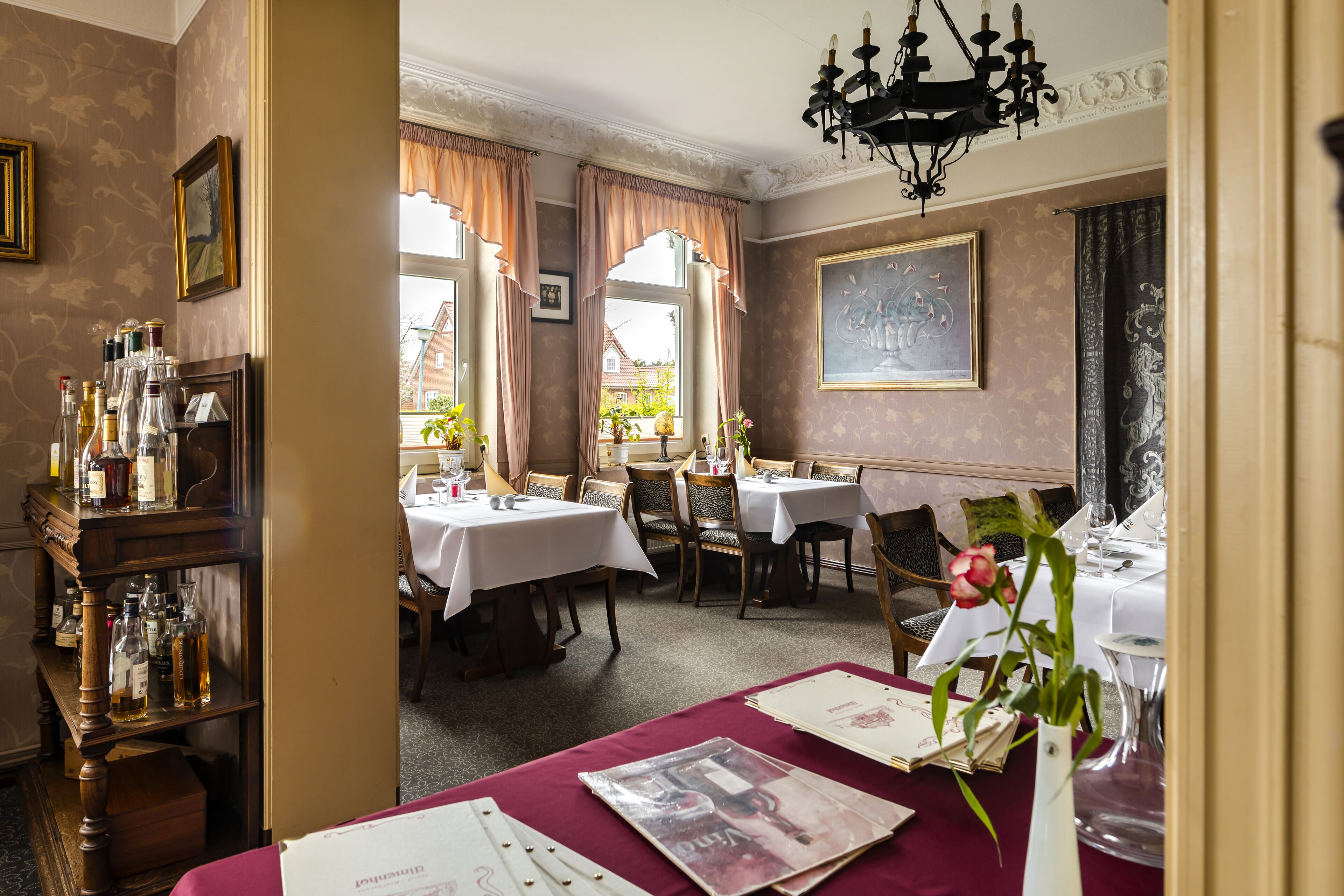 A dining area with tables set for service, a chandelier, and a view of the outside.