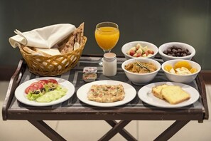 A breakfast tray with various food items including toast, a salad, a bowl of fruit, and a glass of orange juice. - Hotel One Sukkur (Sukkur)