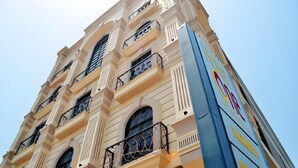 A multi-story building with balconies, large windows, and a blue awning with text. - Hotel One Sukkur (Sukkur)