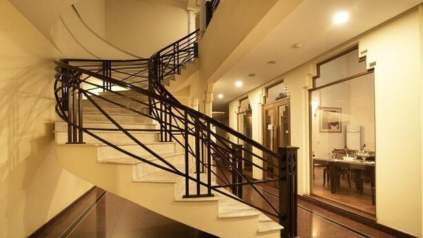 A spiral staircase with black railings in a well-lit hallway. - Hotel One Sukkur (Sukkur)