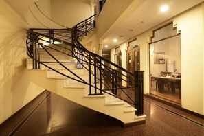 Un escalier en colimaçon avec des rampes noires, situé dans un couloir bien éclairé.