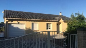A residential house with a garage, a small window, and a metal gate. - Cosy villa in wooded surroundings Heated swimming pool available from May to September (Angomont)