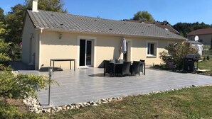 A two-story house with a tiled patio, a dining area with outdoor furniture, and a small garden. - Cosy villa in wooded surroundings Heated swimming pool available from May to September (Angomont)