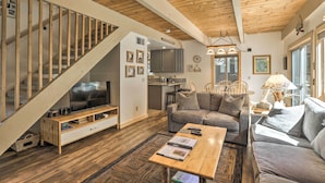 A spacious living room with a wooden staircase, a sofa set, a TV, and a dining area. - 3 Mi to Lake Tahoe: Quiet Incline Village Cabin! (Incline Village)
