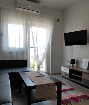 Relax in a serene space with a large window, comfortable sofa, and flat-screen TV.