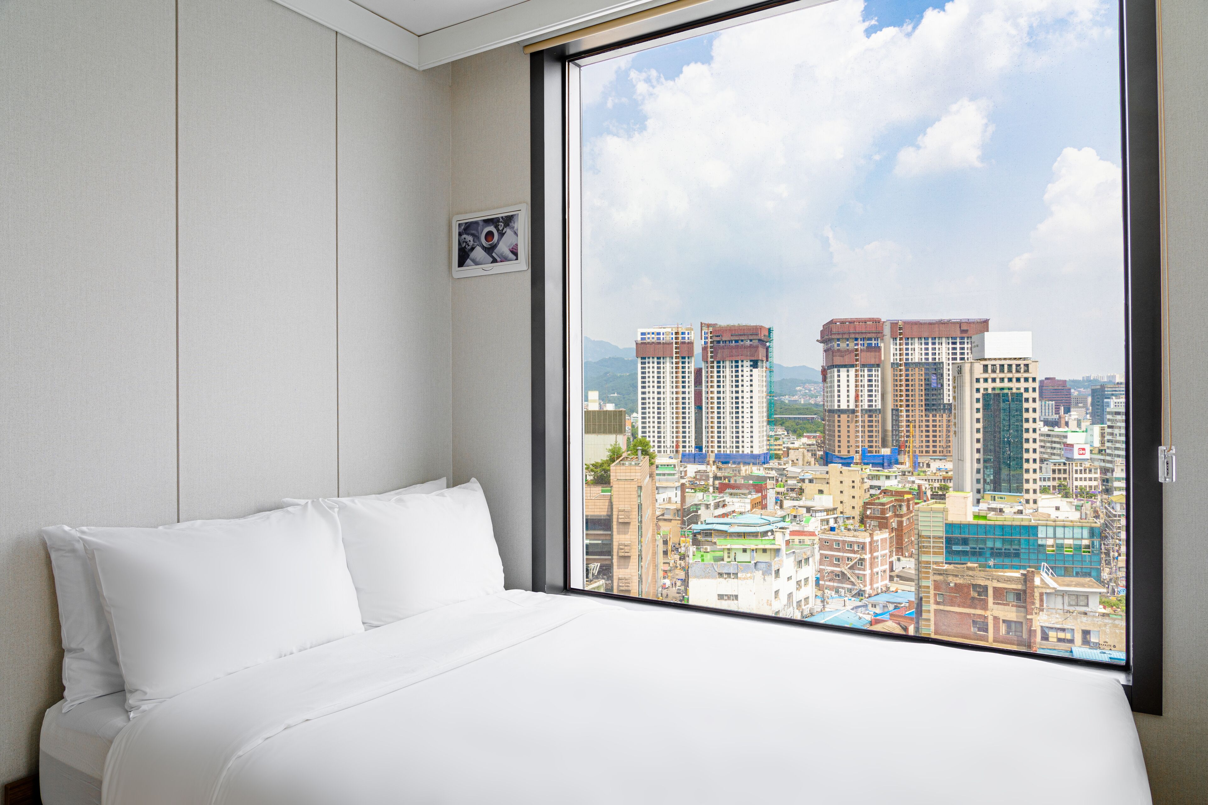 A hotel room with a large window offering a city view.