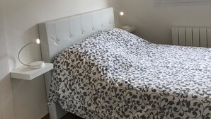 Ein Schlafzimmer mit Bett, Nachttischen, Heizkörper und Fenster.