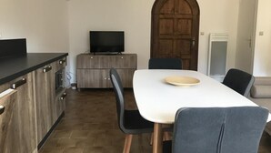 Eine kleine Küche mit Essbereich, Holzschränken, einem Flachbildfernseher und einer großen Bogensturz-Tür.