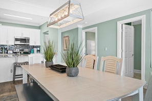 A modern kitchen with white cabinets, a central island, and a hanging light fixture.